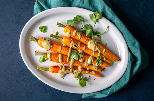 Roasted Carrots with Tahini Sauce on a white plate, with garnish