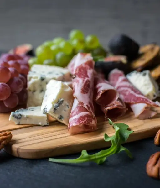 Charcuterie board with figs, crackers, pecans, blue cheese, red and green grapes, and capocollo. Season's Eatings Charcuterie Tasting Event