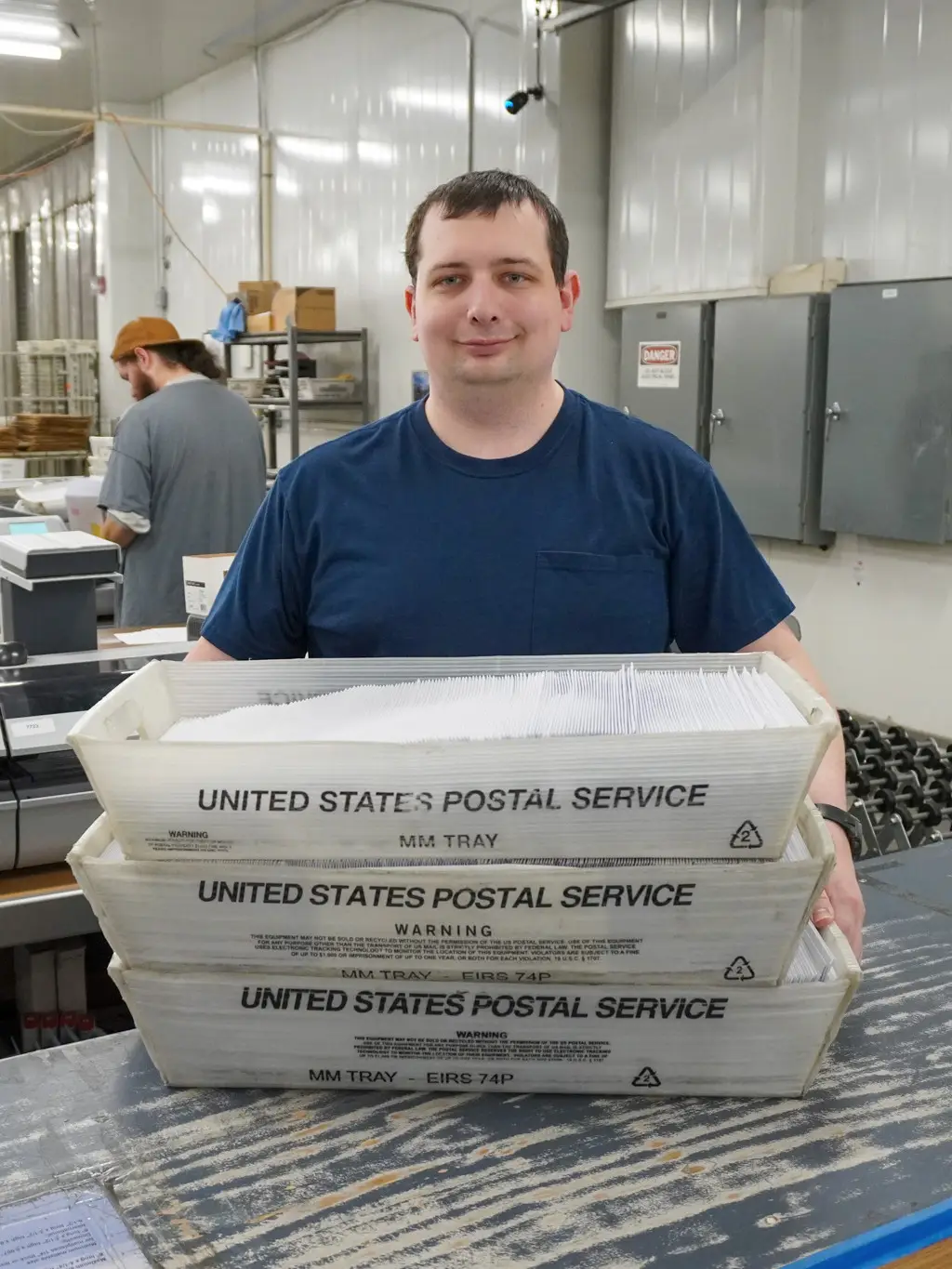 Garten Services participants working in a mailing and shipping area with U.S. Postal Service box.