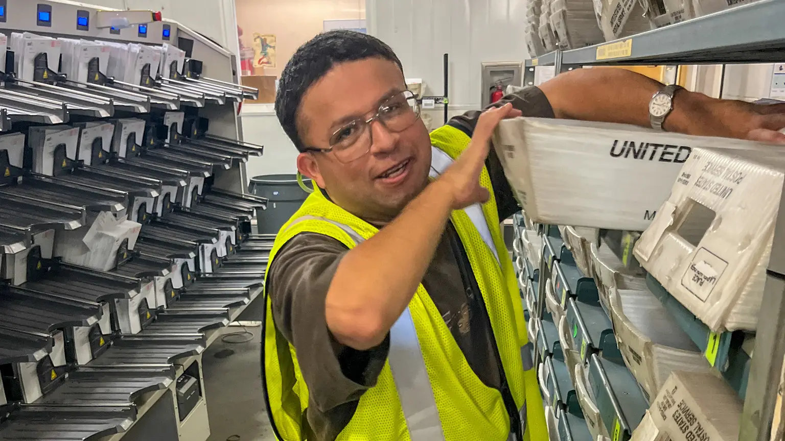 Garten Services employee preparing mail for shipping with U.S. Postal Service boxes visible in the workspace.