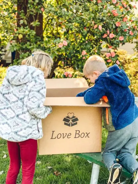 Two children open a Salem Angels Love Box care package.