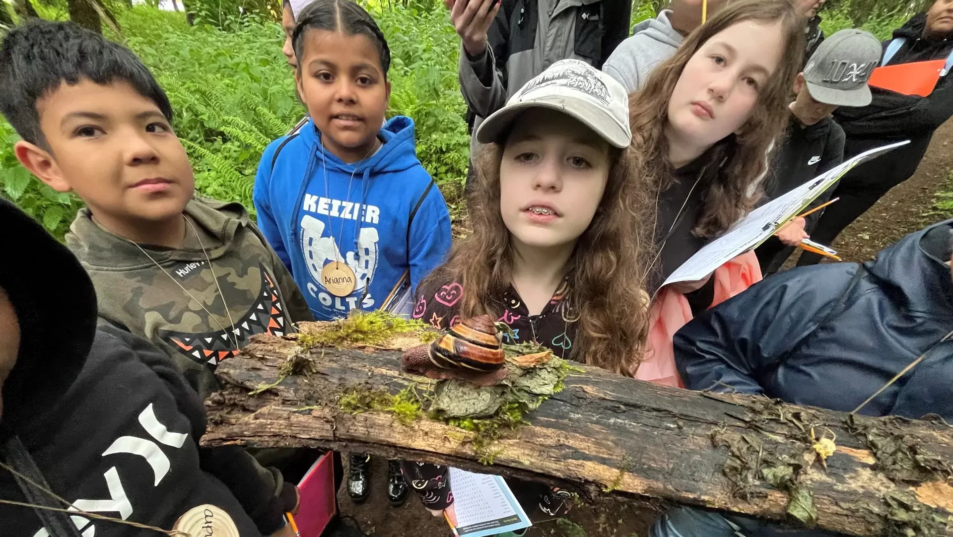 Children from a Salem Environmental education class gather around a branch to look at a snail