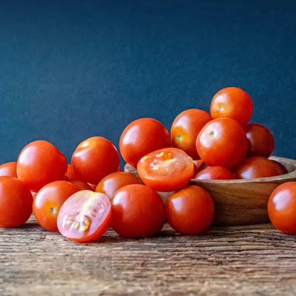 Pile of red cherry tomatoes in a wooden bowl