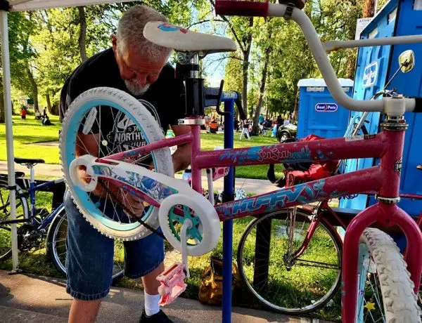 Volunteer repairing a children’s bike at a community event by The Northwest Hub nonprofit in Salem, Oregon