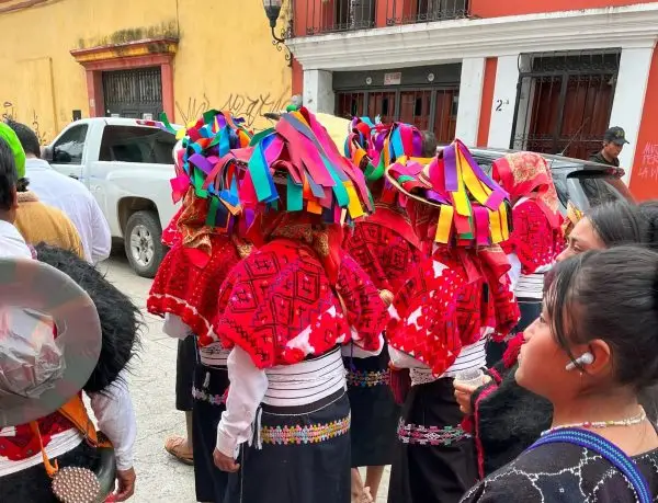 A group of Tzotzil people with red shawls and colorfully ribboned hats.
