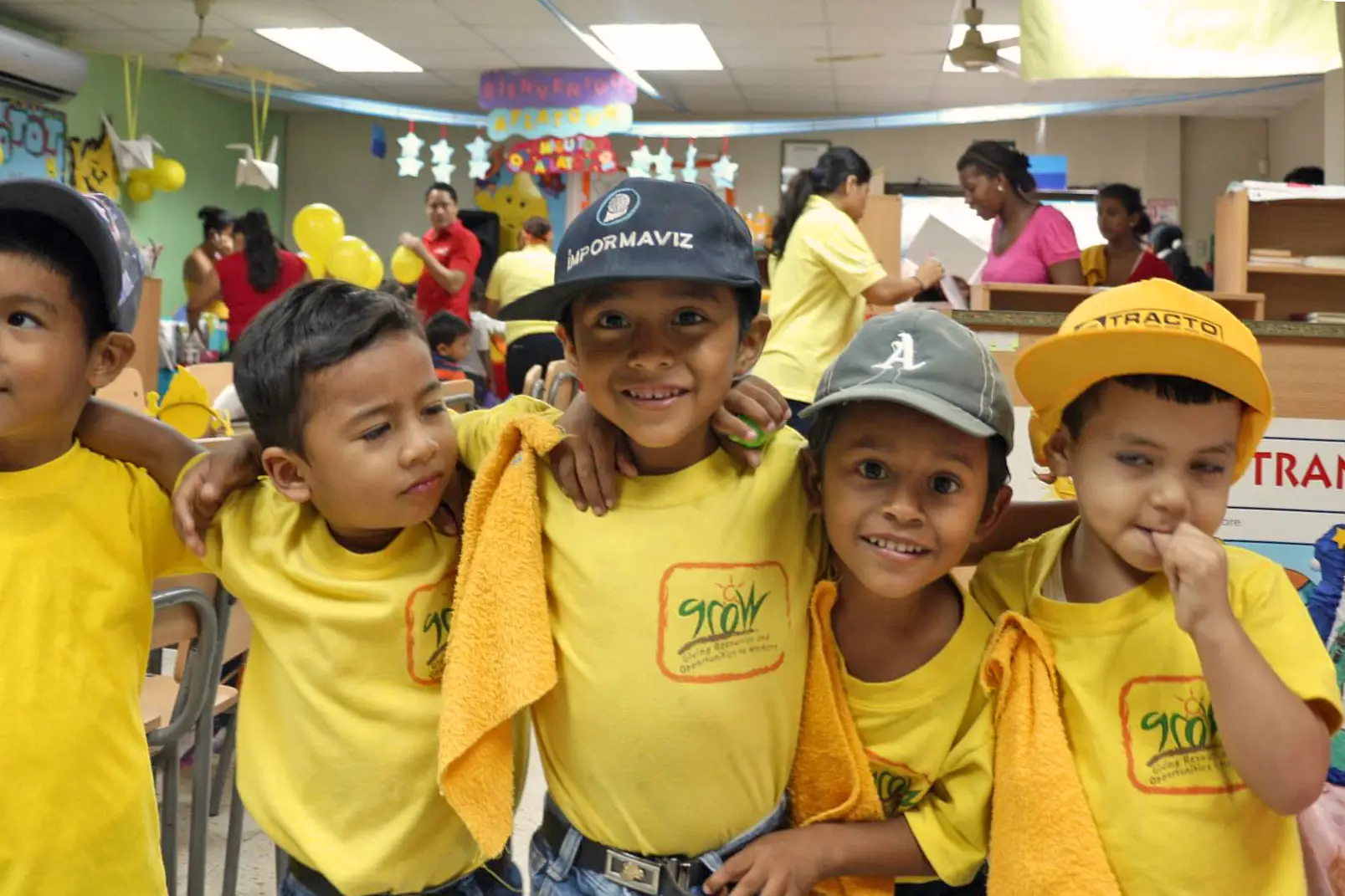 Children wearing yellow GROW shirts gather in a classroom during an educational program supported by GROW fair trade community investments.