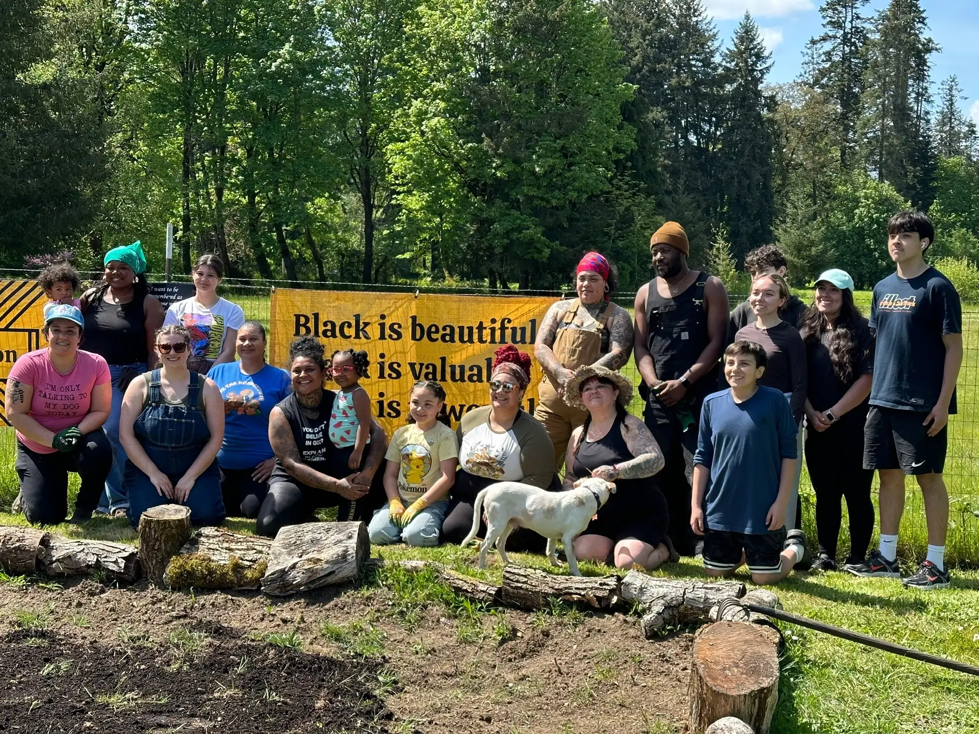 Volunteers gather at Black Joy Farm in front of a banner celebrating community, inclusion, and Black joy during a volunteer workday.