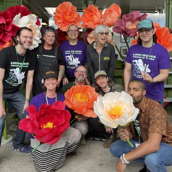 LifeSource team members posing together among colorful oversized paper flowers during Food Fair.