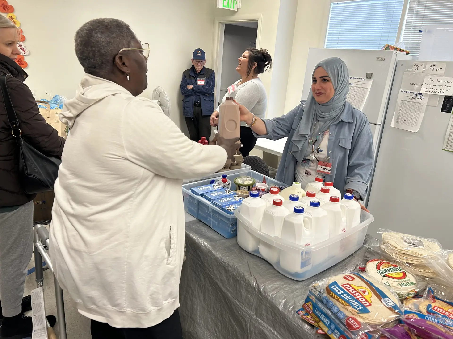 A community member receives milk from an MWVCAA team member at a food distribution event.