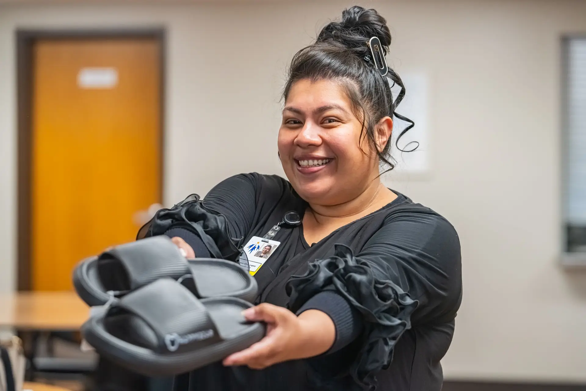 Smiling MWVCAA team member holds out a pair of new shoes for community members in need.