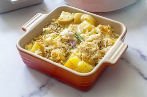 Cheesy potato casserole with tender potato pieces, creamy cheese sauce, herbs, and a golden breadcrumb topping.