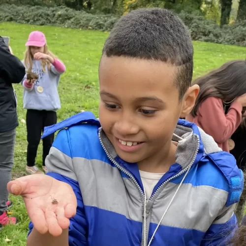 Salem environmental education class looks for small creatures in the soil. Child holding a handful of soil and smiling